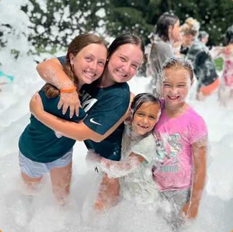 Girls laughing and hugging in a foam party