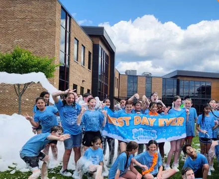 A big group of campers in foam holding a Best Day Ever banner